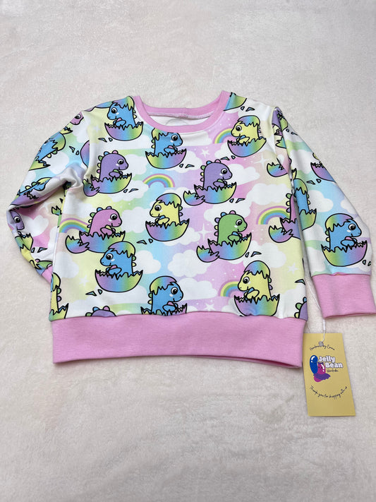 Pastel coloured dinos hatching from eggs on rainbow background 