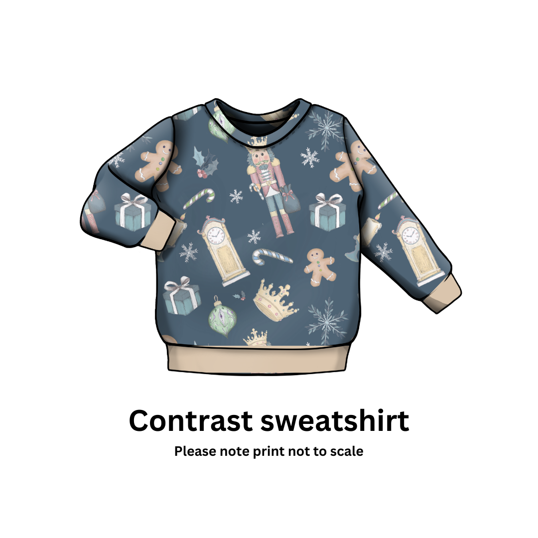 Christmas themed sweatshirt with gingerbread men, nutcrackers, and snowflakes on a blue background.