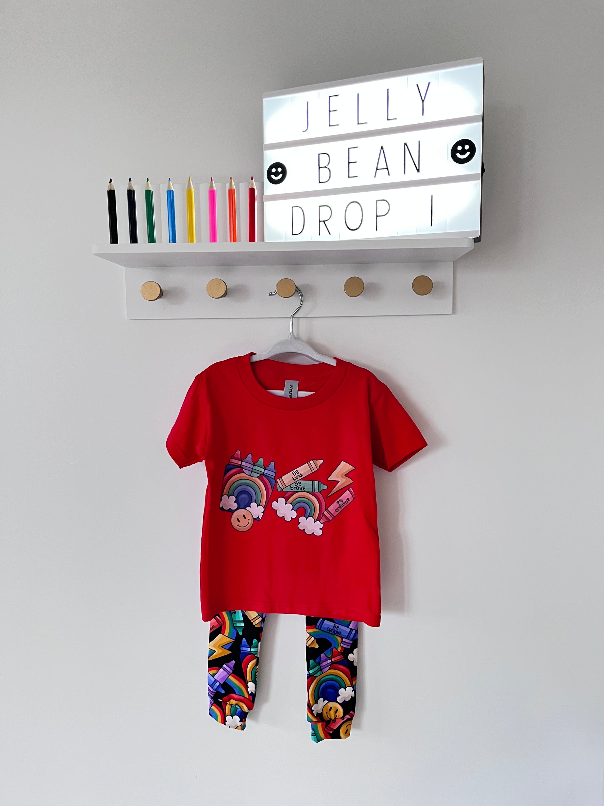 Handmade children’s leggings in a rainbow crayon print, featuring colourful crayons, rainbows, clouds, and positive messages on a dark background.