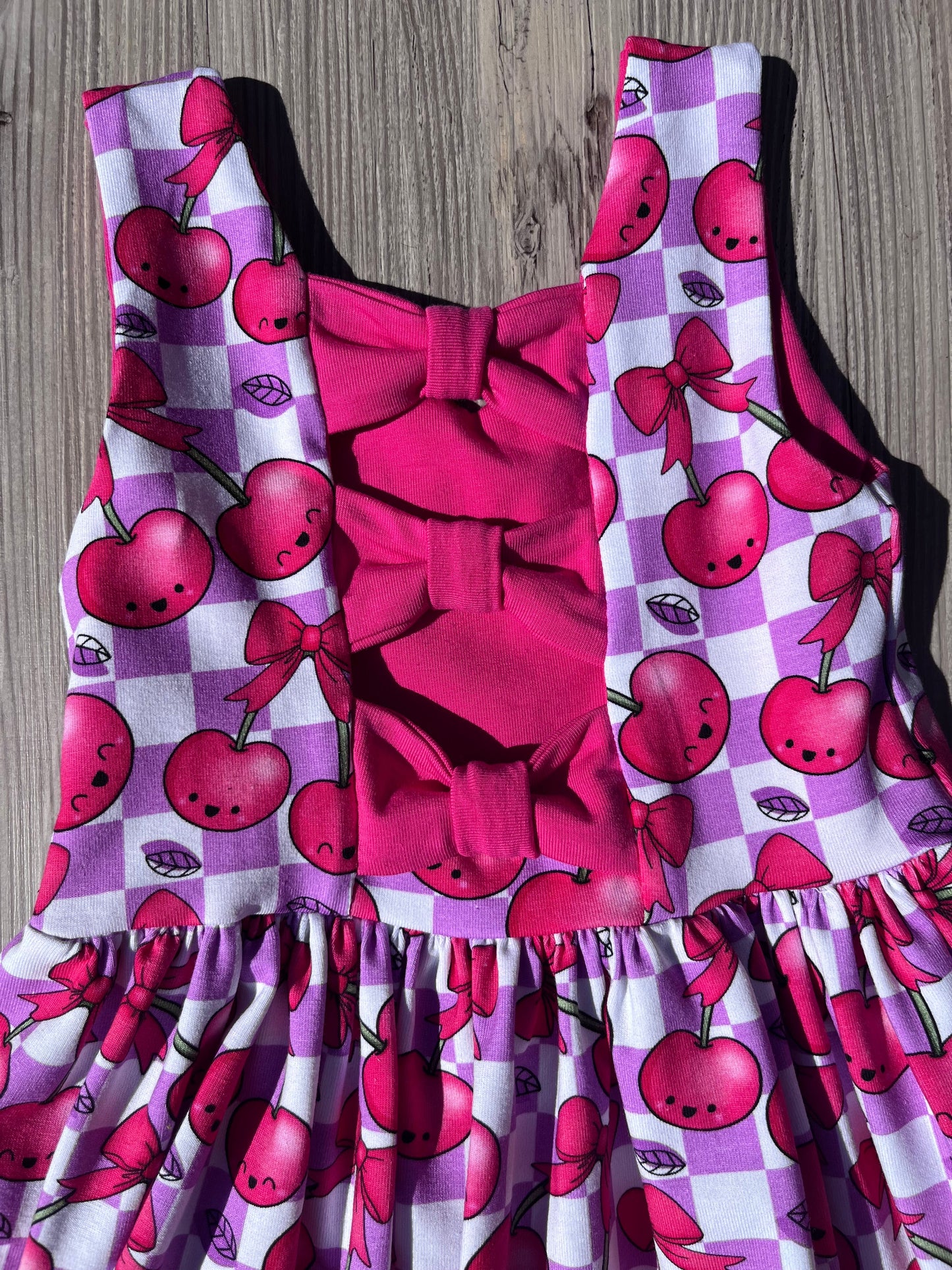 bow back dress with cherry print on a checked background