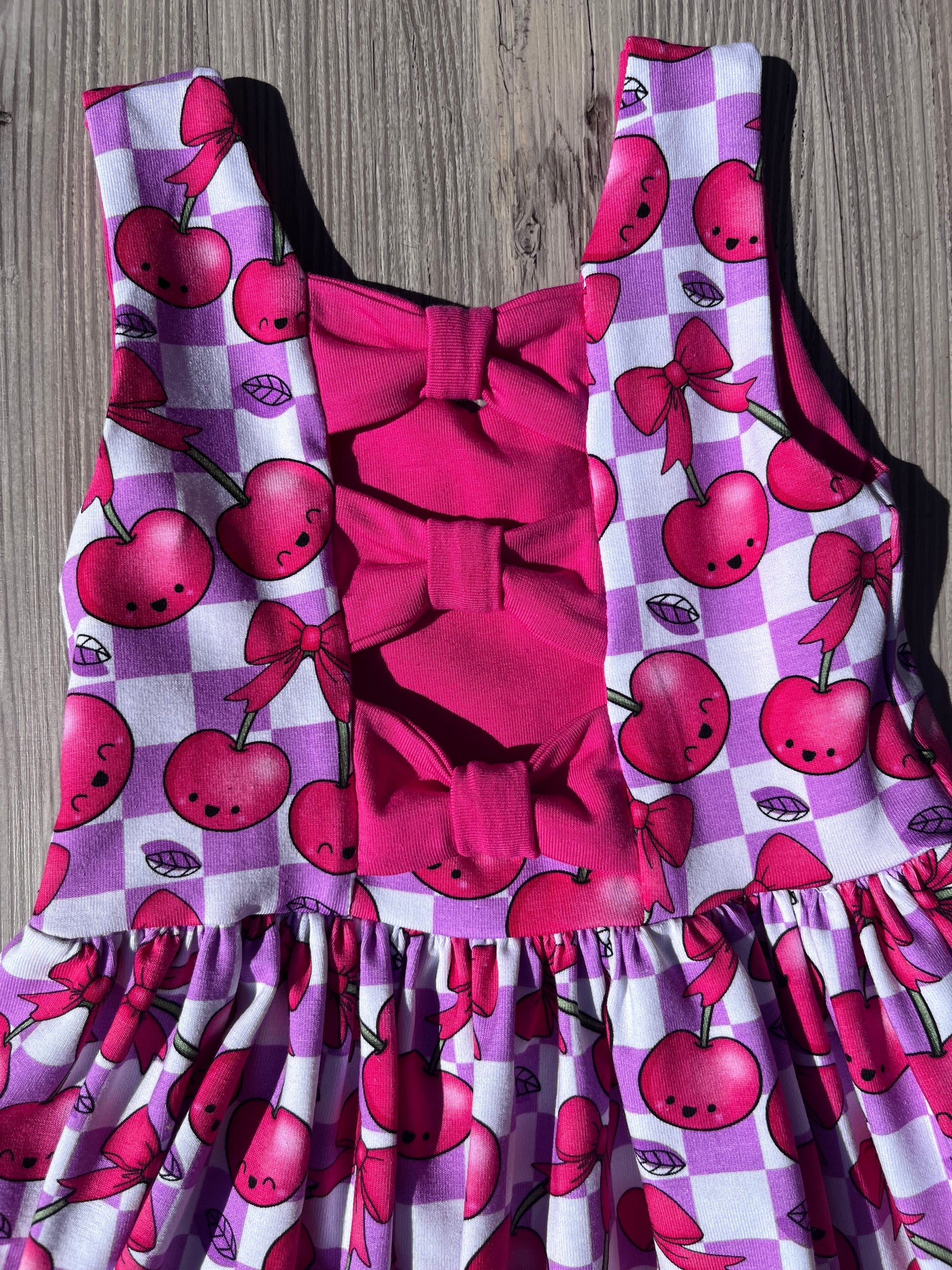 bow back dress with cherry print on a checked background