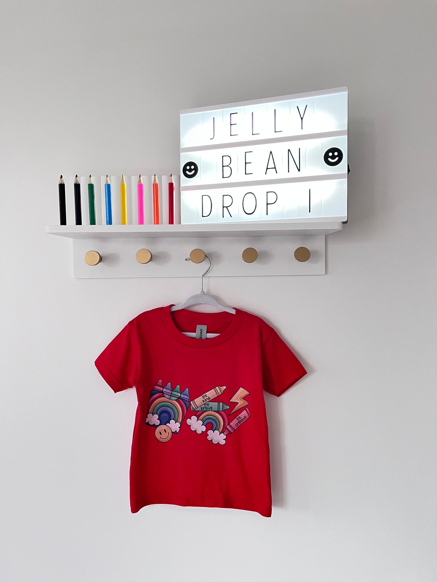 Red t-shirt with colorful design on a white surface next to a box labeled 'Jelly Bean Drop'.